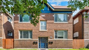 A two-story brick building with a blue front door, windows, and a small front yard. - The Oak | Pet-Friendly King Retreat (Saint Louis)