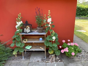 A wooden bench with a lantern, potted plants, and a small table against a red wall. - 5 Star Holiday Home in Otterup (Otterup)