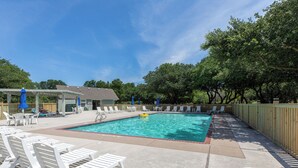 A swimming pool with lounge chairs and umbrellas, surrounded by trees and a wooden fence. - Tuck Away: New Rental, Dog-friendly, Private Pool (Corolla)