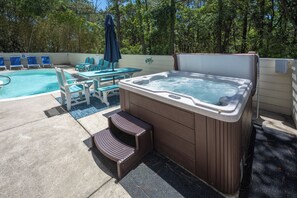 Ein Whirlpool, ein Pool, Liegestühle und ein Tisch mit einem Stuhl.