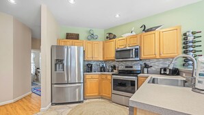 A modern kitchen with stainless steel appliances, wooden cabinets, and a tiled backsplash. - Tuck Away: New Rental, Dog-friendly, Private Pool (Corolla)