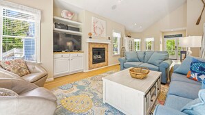 A spacious living room with a fireplace, a television, and a sofa. - Tuck Away: New Rental, Dog-friendly, Private Pool (Corolla)