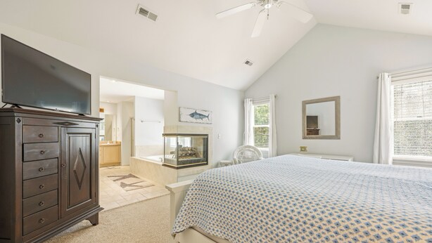 A bedroom with a bed, dresser, television, and a fireplace. - Tuck Away: New Rental, Dog-friendly, Private Pool (Corolla)