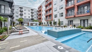 Ein modernes Mehrfamilienhaus mit Schwimmbad, Sitzgelegenheiten im Freien und einem gepflegten Garten.