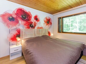 Un dormitorio con una cama grande, un cabecero de madera, una mesita de noche y un mural floral rojo en la pared.