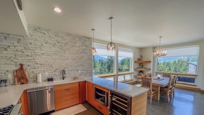 A modern kitchen with a white brick backsplash, wooden cabinets, and a large island. - The Lookout | Wifi, AC, Modern (Packwood)