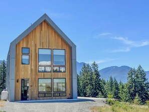 Eine moderne Holzblockhütte mit großen Fenstern und Bergblick.