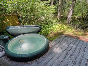 Ein Whirlpool auf einer Holzterrasse, umgeben von dichtem Grün.