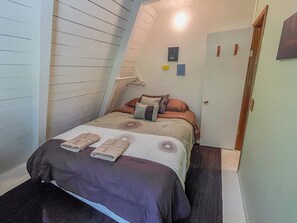 Ein Schlafzimmer mit Bett, Kissen, Nachttisch und Tür.