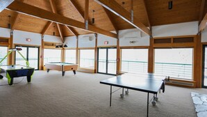 Un espacio interior amplio con mesa de ping pong, mesa de futbolín y mesa de billar.