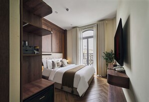 Camera d'albergo moderna con un letto grande, pannelli in legno, una TV a schermo piatto e un balcone con tende.