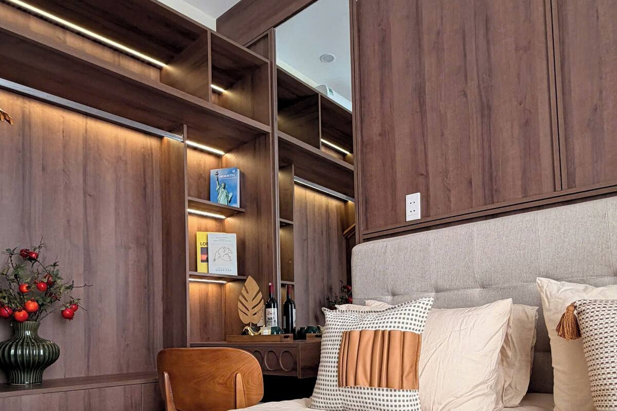 Ein modernes Schlafzimmer mit einem großen Bett, Holzvertäfelung, einem Schreibtisch mit Stuhl und einem Spiegel.