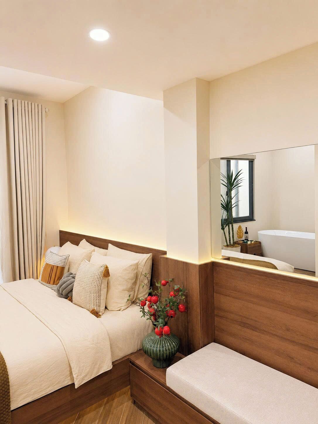A hotel room with a bed, bedside table, and a large mirror.