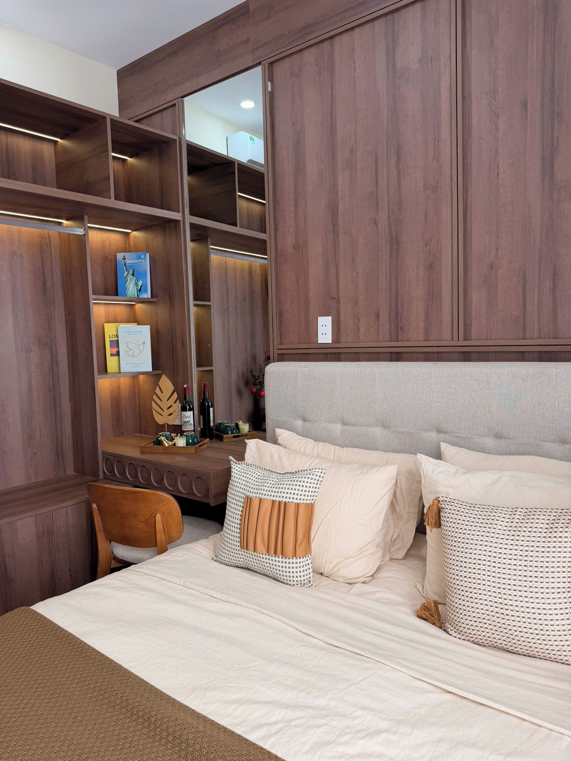 Une chambre à coucher avec un lit, une armoire en bois, une table de chevet et un miroir.
