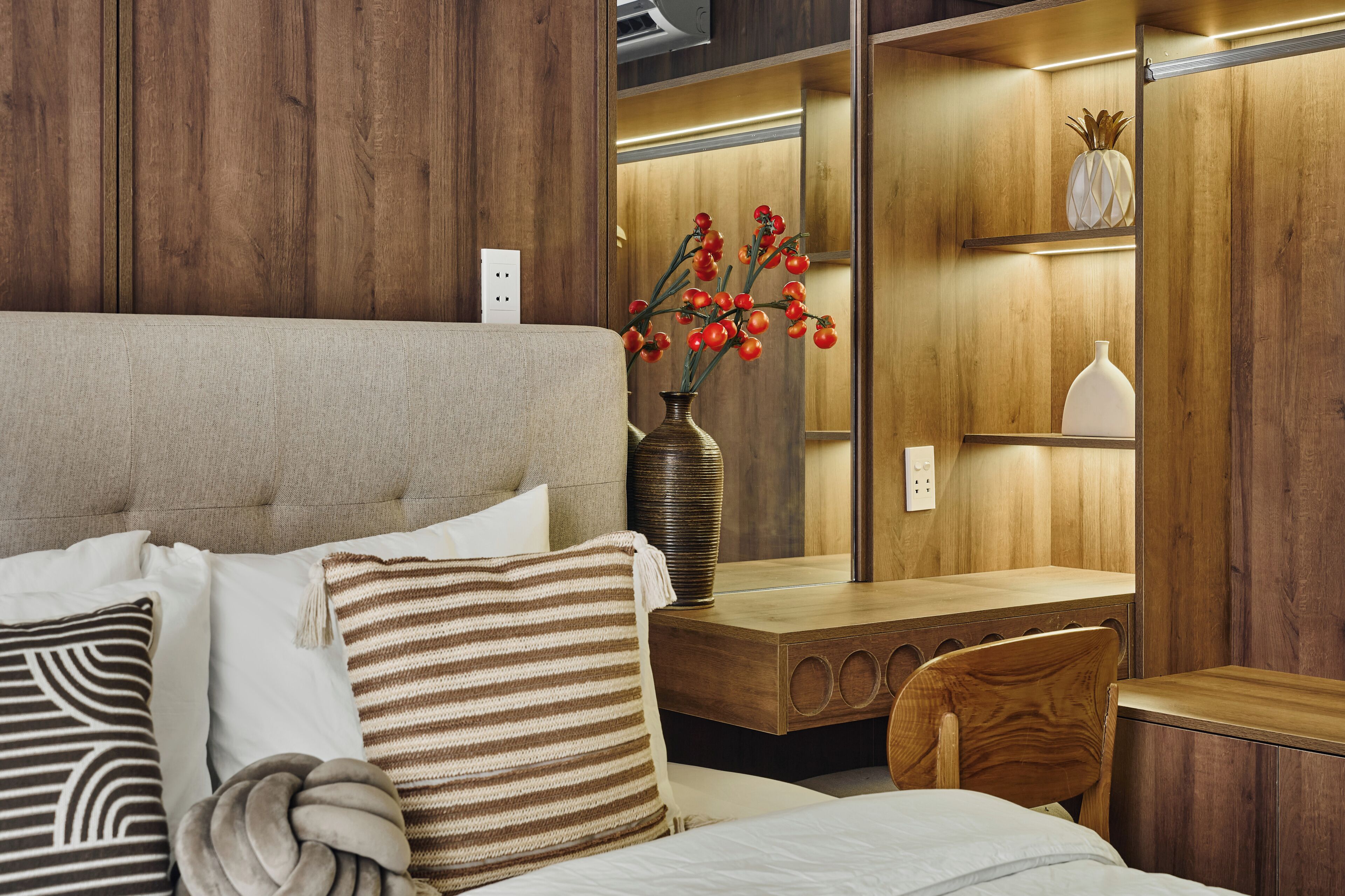 Ein Schlafzimmer mit einem Bett, einem Holztisch, einem Stuhl und einer Vase mit roten Blumen.