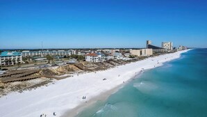 Un hotel frente al mar con vista a la playa, varias edificaciones y una orilla arenosa.