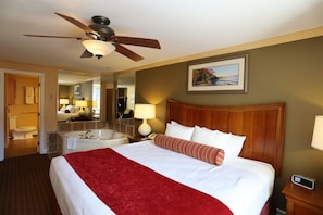 Ein Hotelzimmer mit einem großen Bett, einem Deckenventilator, einem Badezimmer mit Badewanne und einem Bild an der Wand.