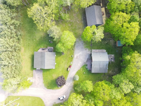 An aerial view of a residential area with two houses, a driveway, and surrounding greenery.