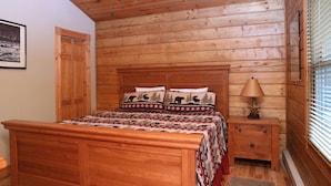 Un dormitorio con paneles de madera, una cama, una mesita de noche, una lámpara y un cuadro en la pared.