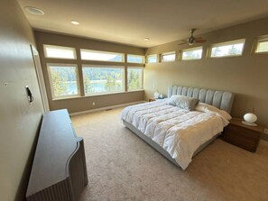 Ein Schlafzimmer mit Bett, Schreibtisch, Stuhl, Deckenventilator und großen Fenstern.