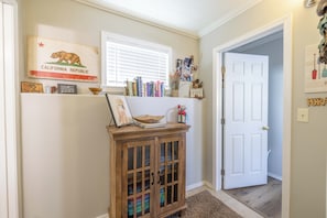 A hallway with a wooden cabinet, a California state flag, and a door leading to another room. - Relaxing Cabin- Hot Tub- Lake View-Fire Pit-Hiking- Walk to Restaurants, Shops (Big Bear Lake)