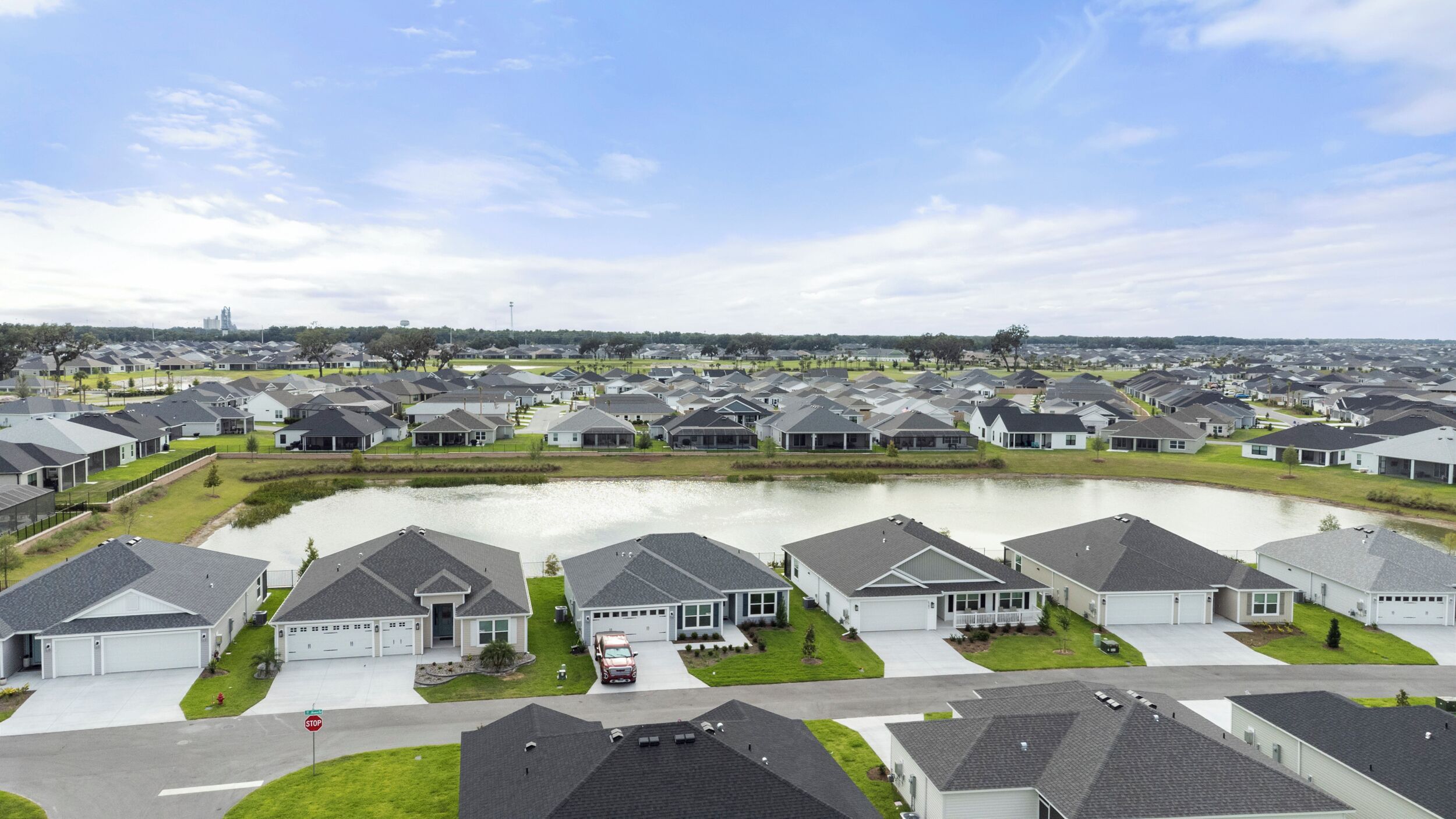 A residential area with houses, a pond, and a stop sign.