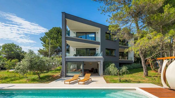 A modern two-story house with a swimming pool, outdoor seating, and a view of the surrounding greenery. - Villa with pool, playground and billiards (Pula)