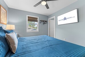 A bedroom with a bed, a ceiling fan, a window with a view, a wall-mounted light, and a door. - Steps to Port of Kimberling & Table Rock Lake_Free Attraction Tickets (Kimberling City)
