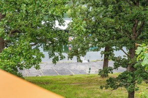 A parking area with trees and a body of water in the background. - Steps to Port of Kimberling & Table Rock Lake_Free Attraction Tickets (Kimberling City)
