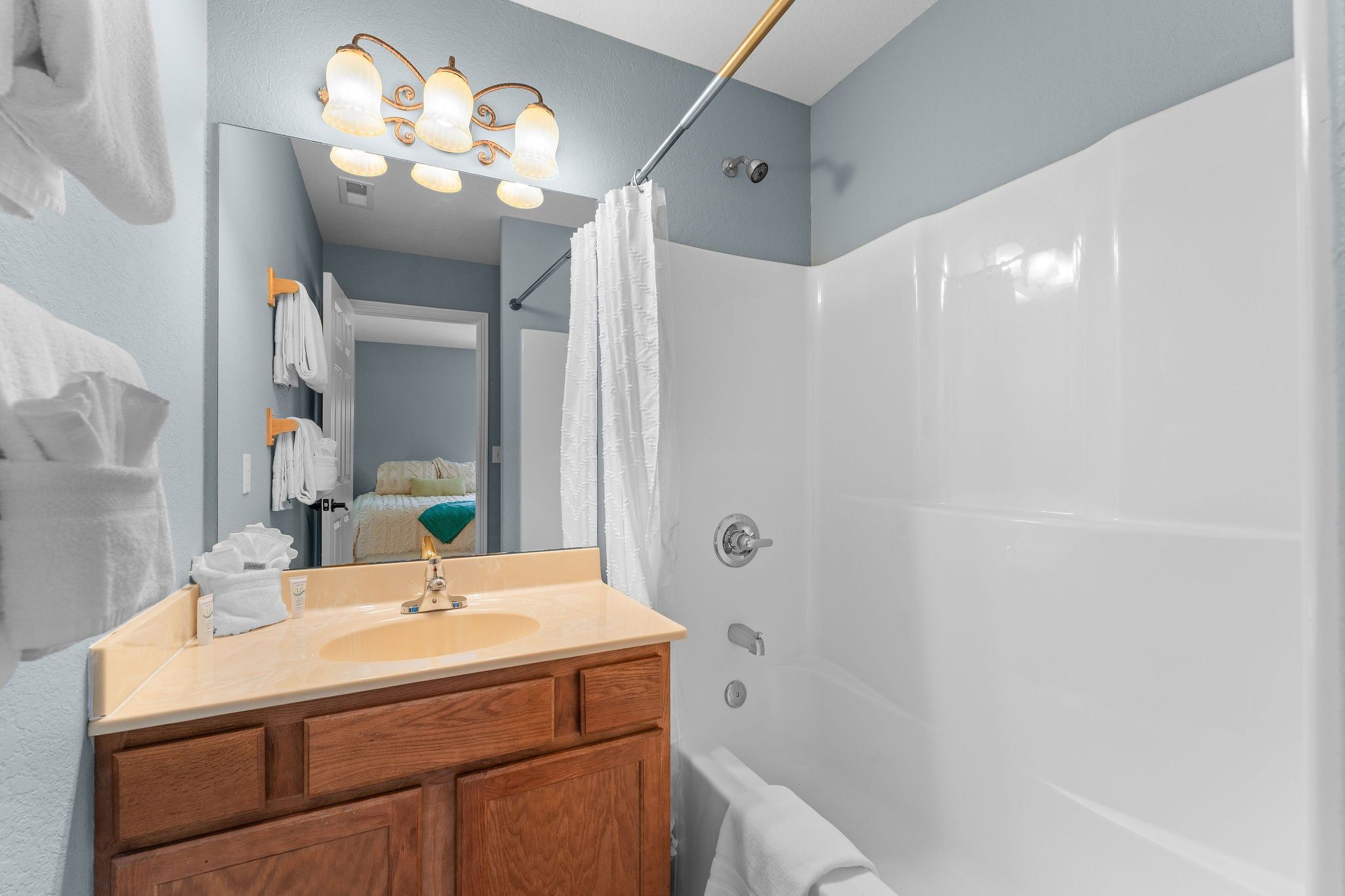 A bathroom with a sink, mirror, shower curtain, and towel rack.