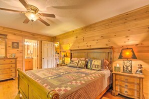 Ein Schlafzimmer mit Holzwänden, einem Bett, Nachttischen und einem Deckenventilator.