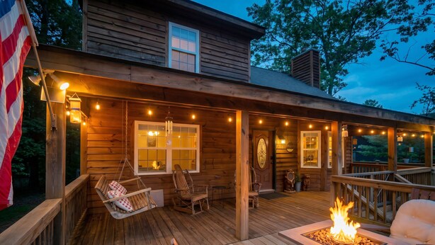Eine Holzterrasse mit hängenden Lichtern, einer Feuerstelle und Sitzgelegenheiten im Freien.