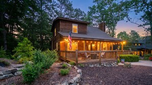 Eine Holzhütte mit Veranda, Steinmauern und einer amerikanischen Flagge.
