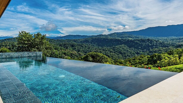 Una piscina infinita con una vista despejada de un paisaje montañoso.