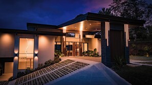 Una casa moderna con un porche cubierto, ventanas amplias y un exterior bien iluminado.