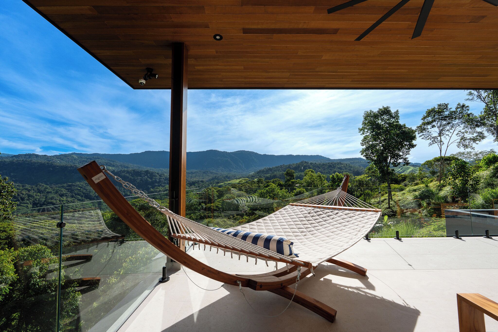 A hammock on a balcony with a view of a mountainous landscape.