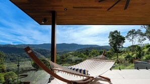 A hammock on a balcony with a view of a mountainous landscape. - 3-bedroom Luxury Villa Dominical Walk to the Waterfalls!! (Dominical)