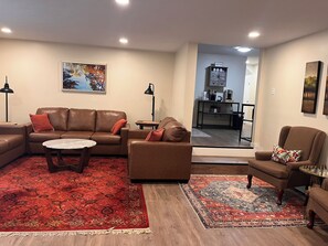 A living room with a brown leather sofa, a coffee table, and a patterned rug.