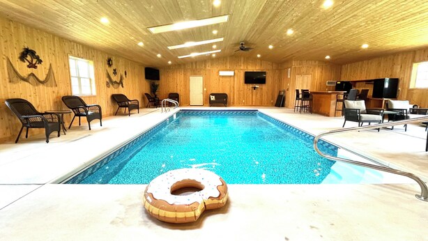Ein Hallenbad mit Holzbalkendecke, Liegestühlen und einem Donut-Schwimmpfiff.