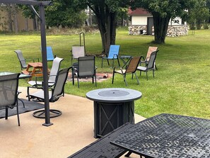 An outdoor patio with a round table, chairs, and a fire pit.