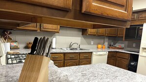 Eine Küche mit Granit-Arbeitsplatten, Holzschränken, einem Gasherd und einem Geschirrspüler.