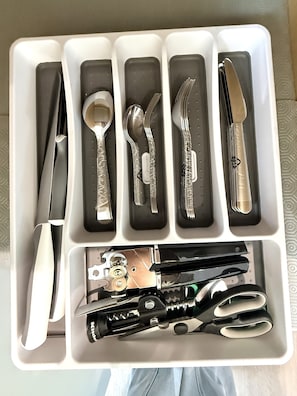 A drawer with utensils and a knife.