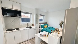 A compact kitchen with a built-in stove, a sink, and a window above the countertop.