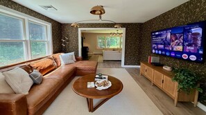 Ein Wohnzimmer mit braunem Ledersofa, einem Holztisch und einem Flachbildfernseher, der eine Streaming-Dienstschnittstelle zeigt.