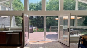 A modern kitchen with a large sliding glass door leading to an outdoor patio area. - Woodland - Stunning 5 bedroom home in GB! (Great Barrington)