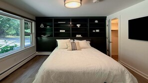 A bedroom with a bed, a window, a built-in shelving unit, and a door leading to a closet. - Woodland - Stunning 5 bedroom home in GB! (Great Barrington)