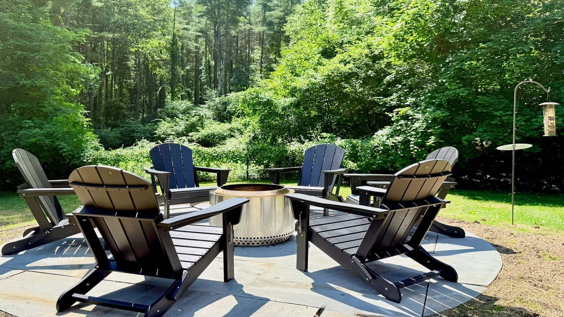An outdoor seating area with Adirondack chairs around a central fire pit.