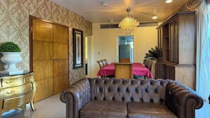 A room with a tufted leather sofa, a wooden cabinet, a dining table with a red tablecloth, and a chandelier. - LUXURY APARTMENT IN ASUNCIÓN, PARAGUAY: THE TOWER (Asunción)