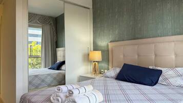 Une chambre d’hôtel avec un lit, une table de chevet, une lampe et un miroir.