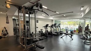 A gym with various exercise equipment, including treadmills and weight machines, with a large window providing a view of the outdoors. - LUXURY APARTMENT IN ASUNCIÓN, PARAGUAY: THE TOWER (Asunción)
